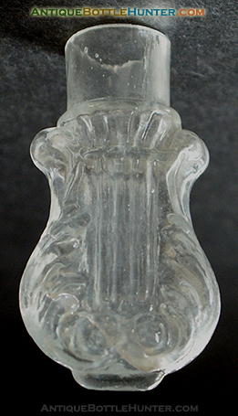 A colorless scroll or lyre type mold blown smelling bottle. --- AntiqueBottleHunter.com